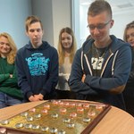 Grupa uczniów patrzy na planszę chińskich szachów