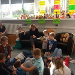 uczniowie klasy 2 PA siedzą na podłodze słuchając utworów czytanych przez nauczyciela