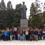 Uczniowie stojący przed pomnikiem Marii Skłodowskiej Curie